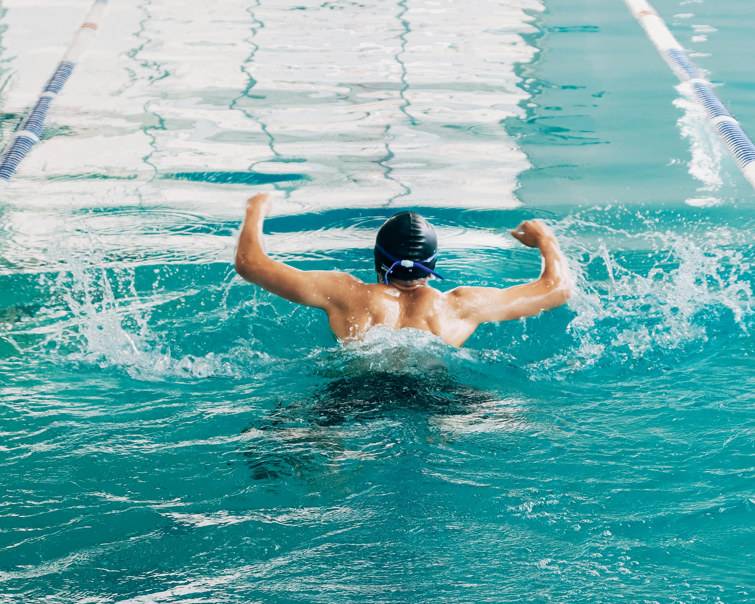 Professional swimmer in action during a practice session in an indoor pool, perfecting butterfly stroke.