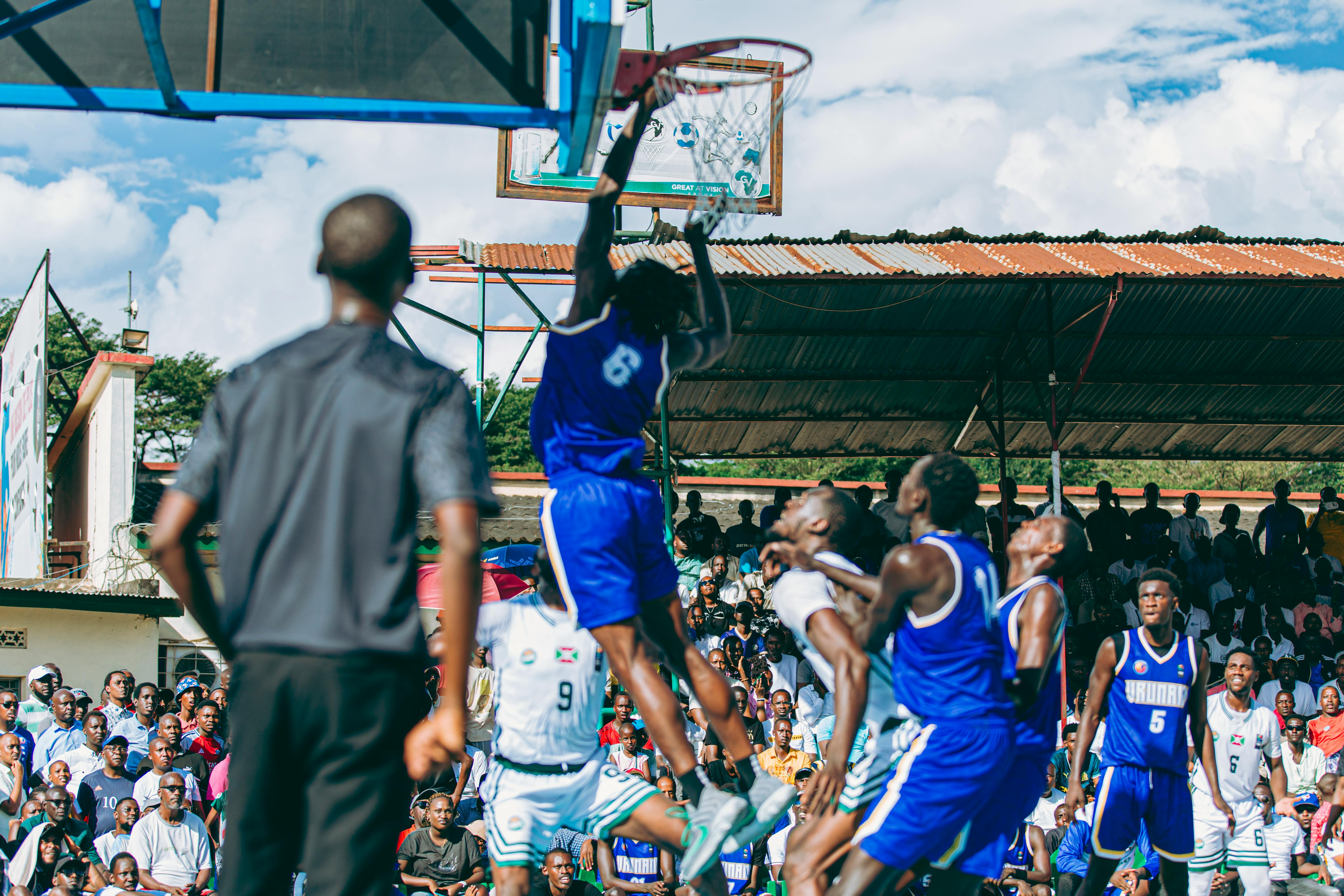 Intense basketball game with players in action on an outdoor court, drawing a lively crowd.