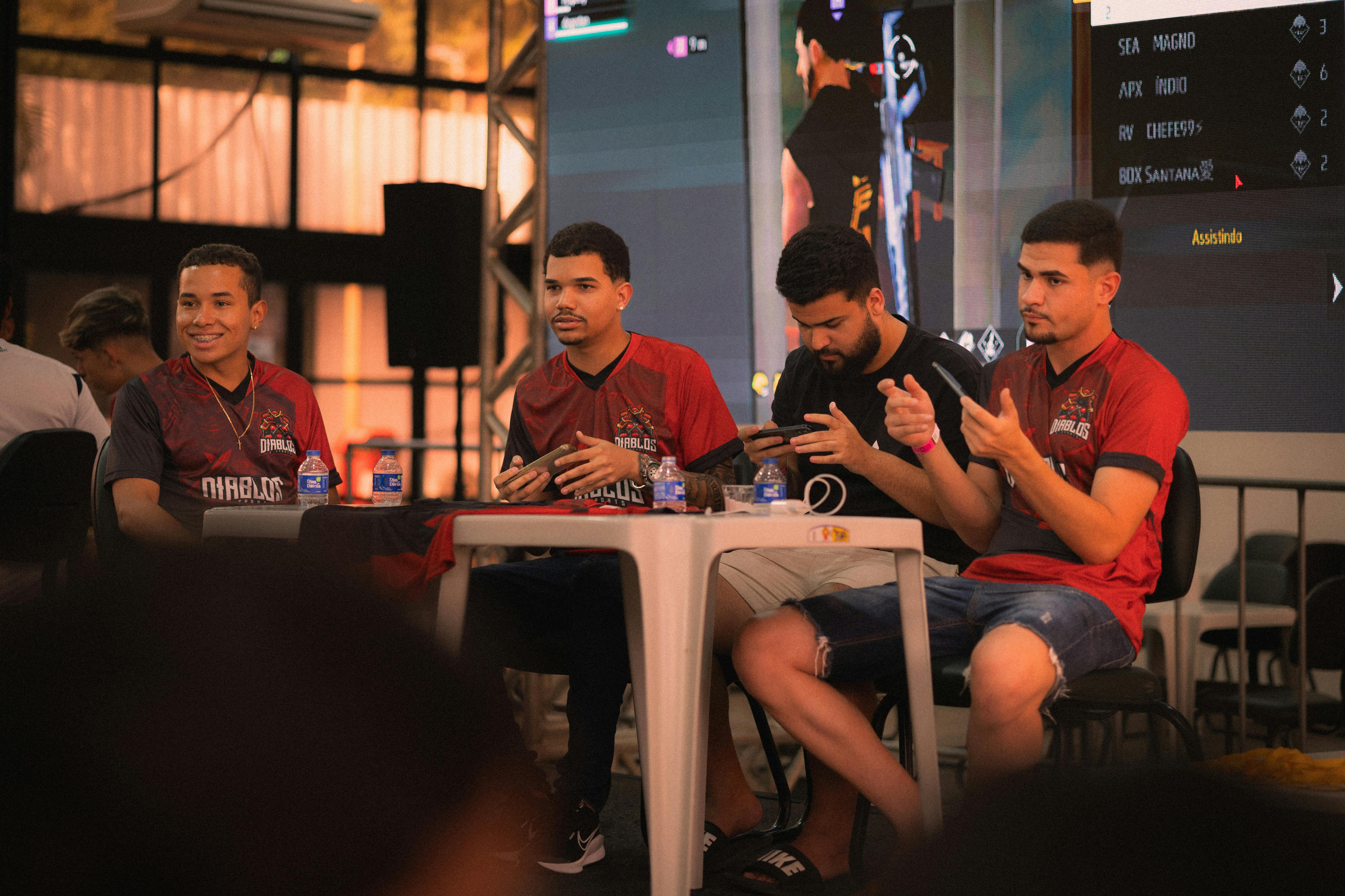 A group of e-sports players participating in a gaming event, focused on smartphone gameplay.