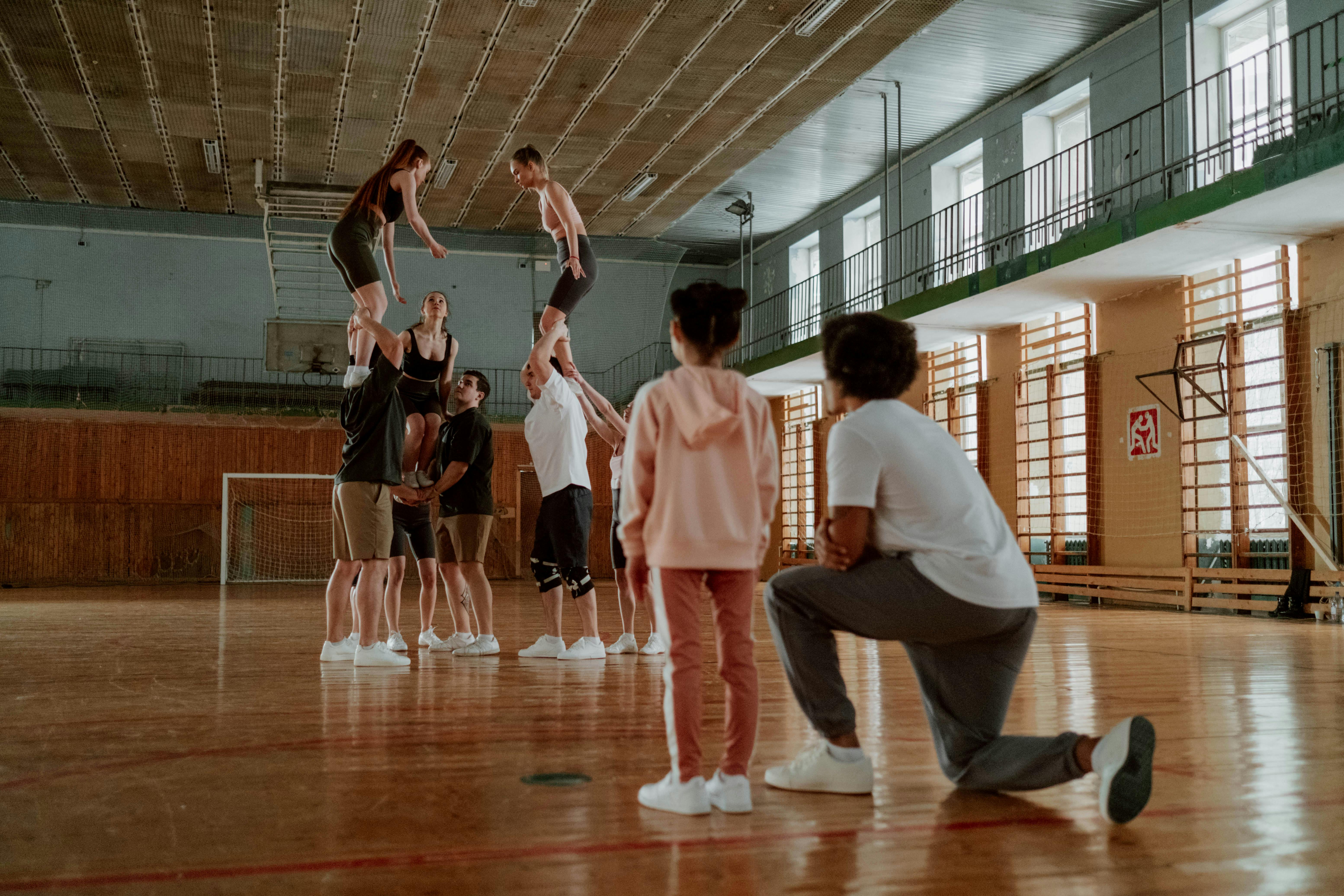 Group of athletes rehearsing cheerleading moves indoors.